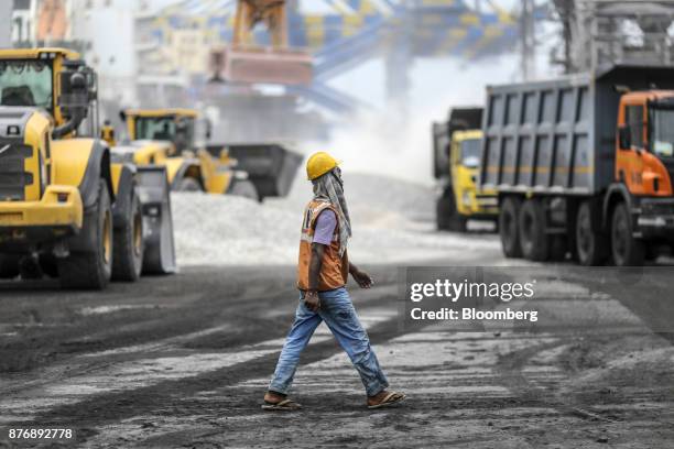 Worker walks along the dock as materials are unloaded from a ship, not pictured, at Krishnapatnam Port in Krishnapatnam, Andhra Pradesh, India, on...