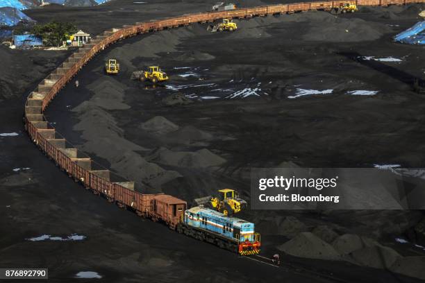 Front-loaders arrange stacks of coal as a freight train sits on rail tracks at Krishnapatnam Port in Krishnapatnam, Andhra Pradesh, India, on...