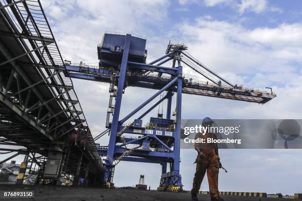 Worker walks alongside a conveyor running past a gantry crane at Krishnapatnam Port in Krishnapatnam, Andhra Pradesh, India, on Friday, Aug. 11,...