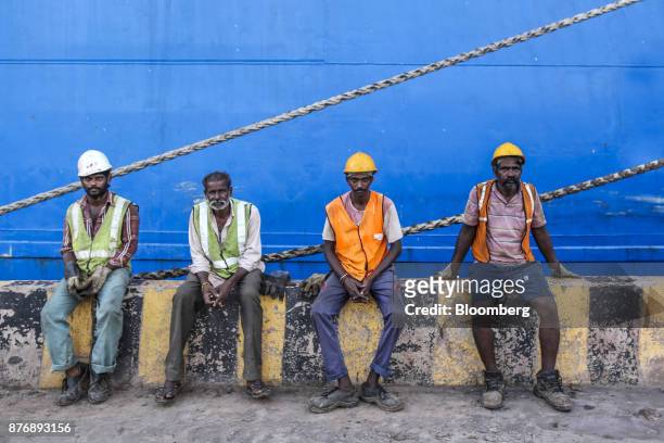 Workers sit in front of the Da Dan Xia cargo ship, not pictured, at Krishnapatnam Port in Krishnapatnam, Andhra Pradesh, India, on Friday, Aug. 11,...
