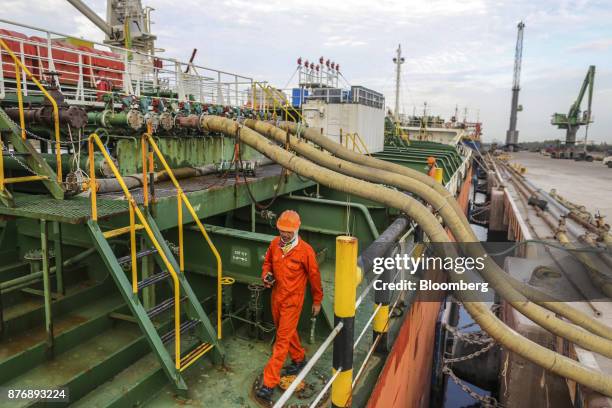 Workers supervise edible oil being moved on the Gandawati Tarawa tanker while docked at Krishnapatnam Port in Krishnapatnam, Andhra Pradesh, India,...
