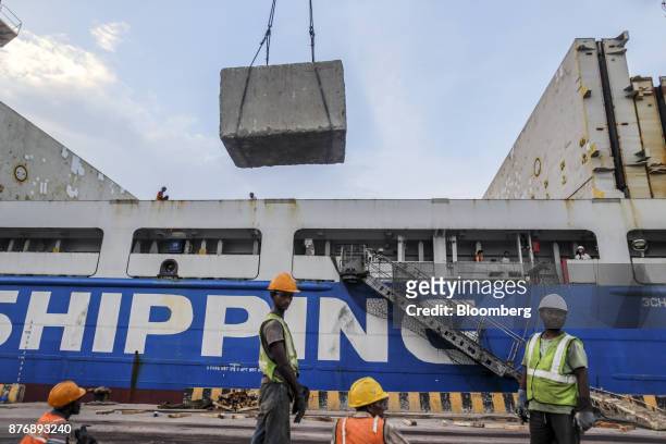 Workers supervise a block of limestone being loaded on to the Da Dan Xia cargo ship at Krishnapatnam Port in Krishnapatnam, Andhra Pradesh, India, on...