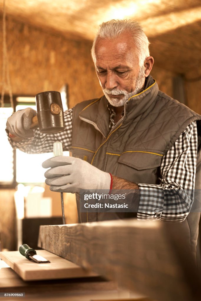 Mature carpenter using hammer