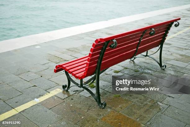 empty red bench on a rainy day - canale della giudecca stock pictures, royalty-free photos & images