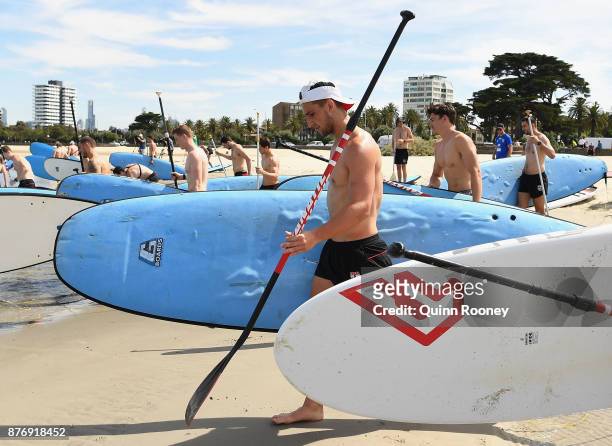 Luke Dunstan of the Saints walks into the water with his team mates to do stand up paddleboarding during a St Kilda Saints AFL training session at...