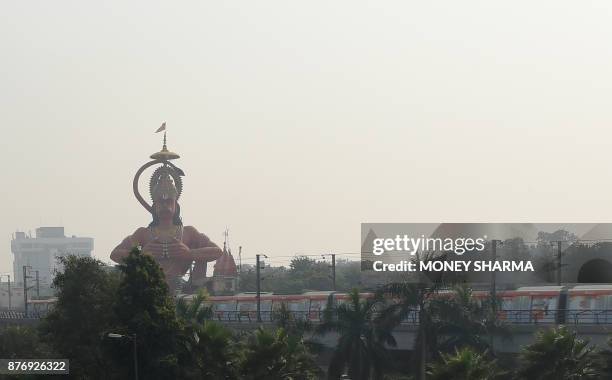 An Indian metro train passes by a 108-foot statue of Hindu god Lord Hanuman in New Delhi on November 21, 2017. The Delhi High court has suggested...