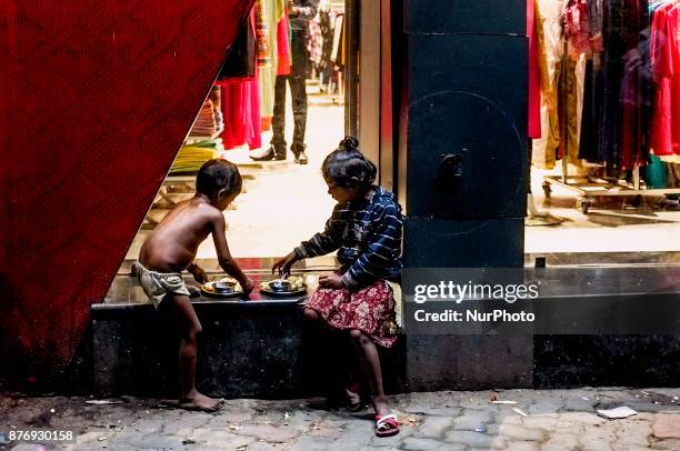 Two street urchin are having food on the pavement next to a lifestyle-fashion store at Calcutta / Kolkata.