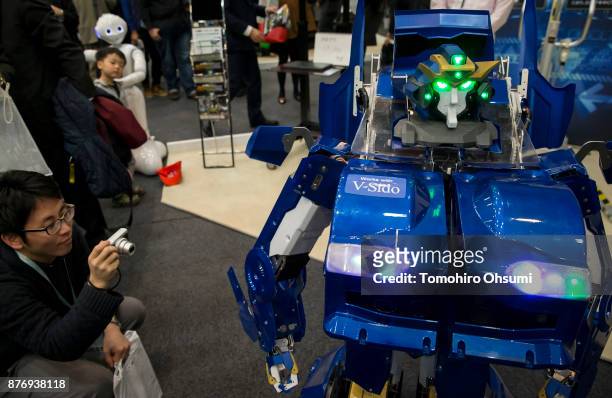 Visitor takes a photograph of the J-Deite Quarter transforming robot being demonstrted during the SoftBank Robot World 2017 on November 21, 2017 in...