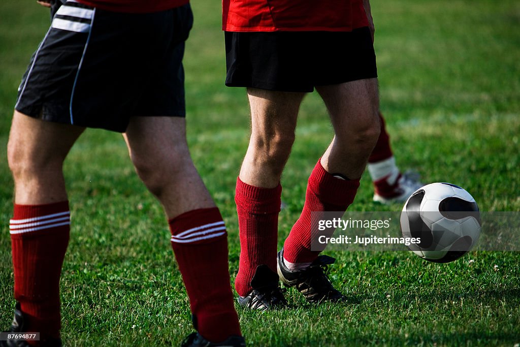 Legs of soccer players with ball