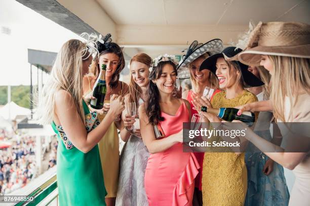 gruppe junger frauen, die eine flasche champagner öffnen - kopfschmuck stock-fotos und bilder