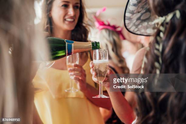 verter el champagne con amigos - fascinator fotografías e imágenes de stock