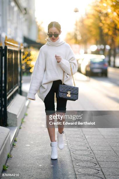 Rosa Crespo, fashion blogger, wears a Dior studded bag, Barney white boots, sunglasses, an Acne Studios white oversize sleeves sweater and a...