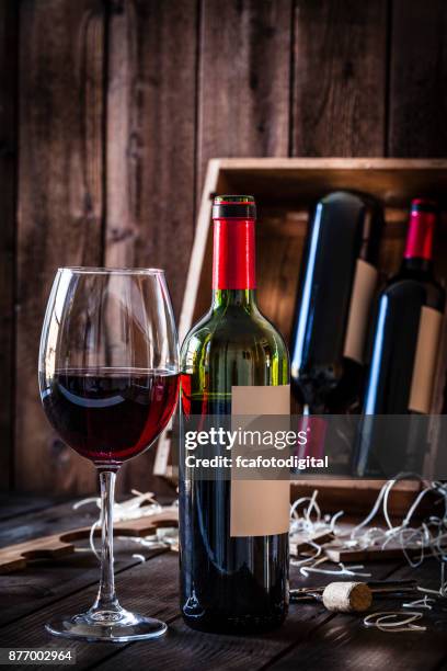 wineglas and red wine bottle shot rustic wooden table - wine bottle transport stock pictures, royalty-free photos & images