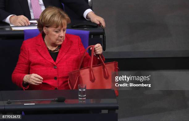 Angela Merkel, Germany's chancellor, holds her handbag inside the lower-house of the German Parliament in Berlin, Germany, on Tuesday, Nov. 21, 2017....