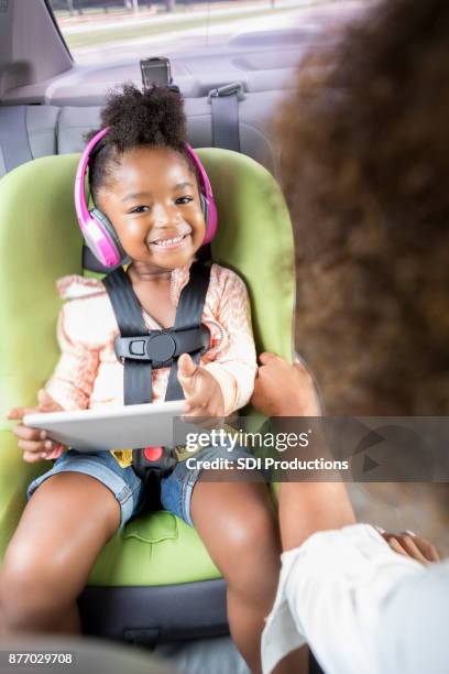 adorable girl plays with digital tablet while traveling - girl in car with ipad stock pictures, royalty-free photos & images