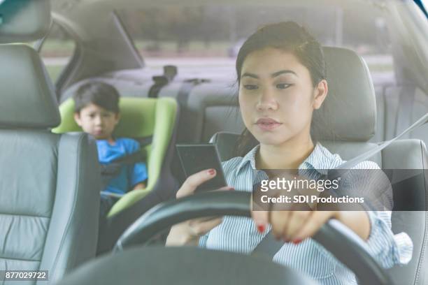 媽媽在開車的時候帶著孩子在後座 - distracted 個照片及圖片檔
