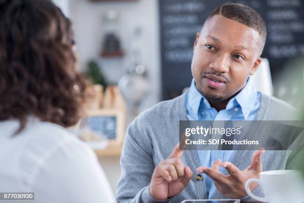interviewer outlines job responsibilities during coffee shop interview - sneering stock pictures, royalty-free photos & images