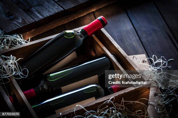 botellas de vino rojo embalan en una caja de madera rústica mesa de madera de tiro - vinos fotografías e imágenes de stock