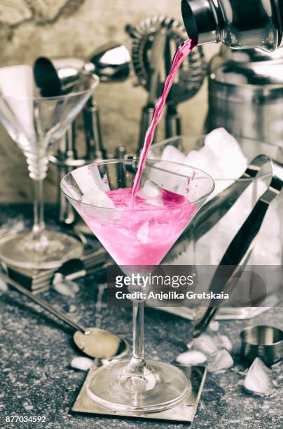 pink cocktail pouring from shaker in a glass - icepick stock-fotos und bilder