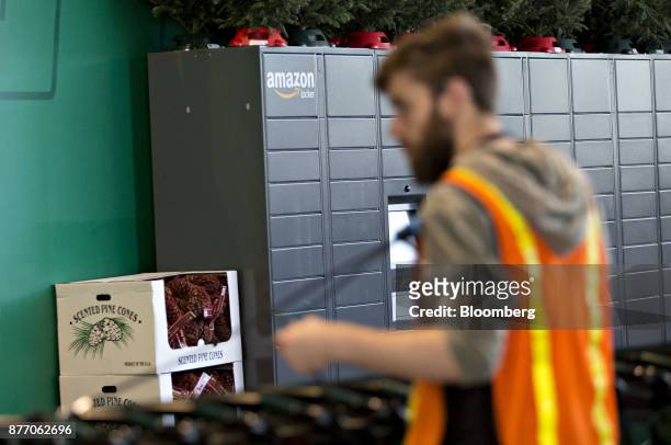 An employee organizes shopping carts in front of a wall of Amazon.com Inc. Lockers, a self-service parcel delivery service, inside the Lakeview Whole...