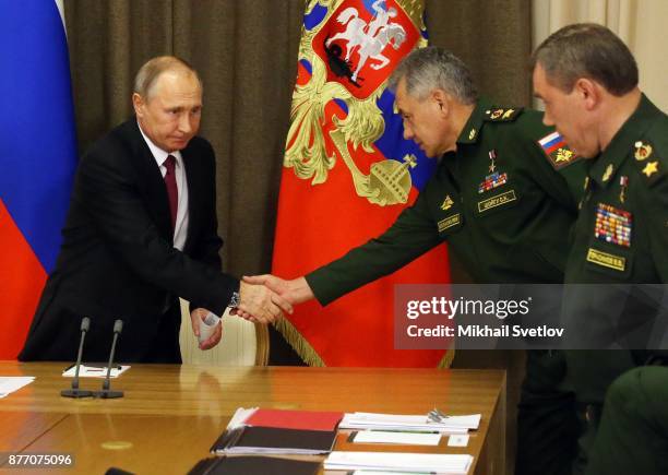 President Vladimir Putin shakes hands with Defence Minister Sergey Shoigu during his meeting with Defence Ministry and military industry officials at...