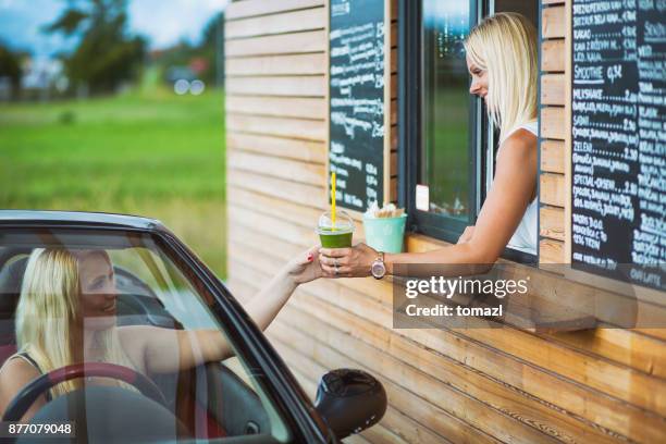 drive-in caffe female clerk with smoothie - drive through stock pictures, royalty-free photos & images