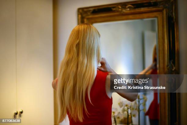 young woman in red dress standing in front of a mirror - woman mirror dress stock-fotos und bilder