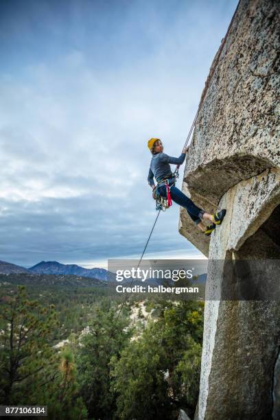 donna arrampicata su roccia alle prese con lo strapiombo - rock overhang foto e immagini stock