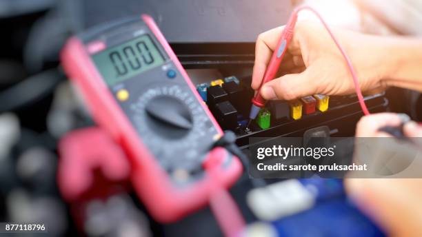 selective focus an auto mechanic uses a multimeter voltmeter to check the voltage level in a car battery. - voltmeter stock pictures, royalty-free photos & images