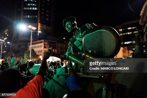 Zimbabwean soldier sitting in tank gestures as people greet and celebrate after the resignation of President Mugabe in Harare on November 21, 2017....