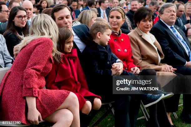 Ivanka Trump looks on as Tiffany Trump kisses brother in law and Senior Advisor to the President Jared Kushner as they sit with Trump's grandchildren...