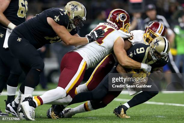 Drew Brees of the New Orleans Saints is sacked Kevin Bowen of the Washington Redskins and Ryan Kerrigan of the Washington Redskins during the second...