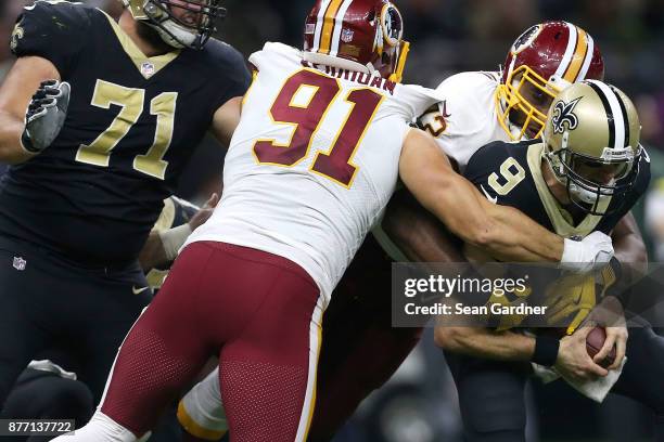 Drew Brees of the New Orleans Saints is sacked Kevin Bowen of the Washington Redskins and Ryan Kerrigan of the Washington Redskins during the second...