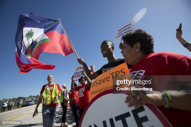 Demonstrators hold signs and wave flags during a protest ahead of the arrival of U.S. President Donald Trump at Mar-a-Lago in West Palm Beach,...