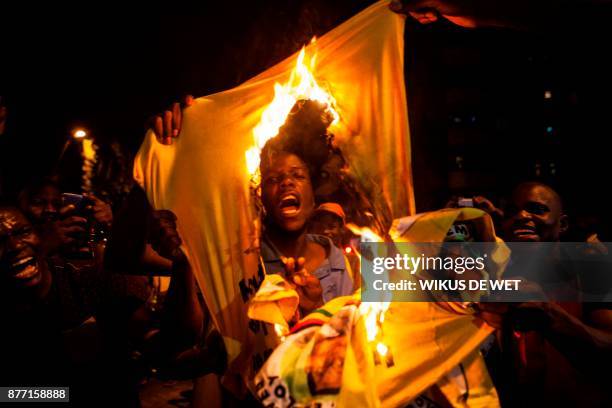 Zimbabwean national burns a shirt of the Zimbabwe's ruling party, the Zimbabwe African National Union Patriotic Front , as hundreds of Zimbabweans...