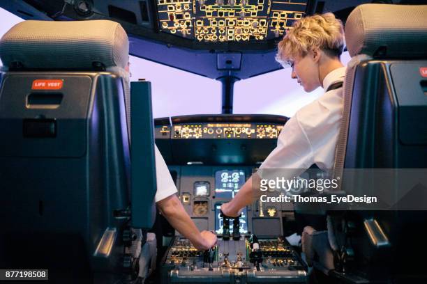 trainee pilot operating throttle in flight simulator with instructor - airline pilot imagens e fotografias de stock