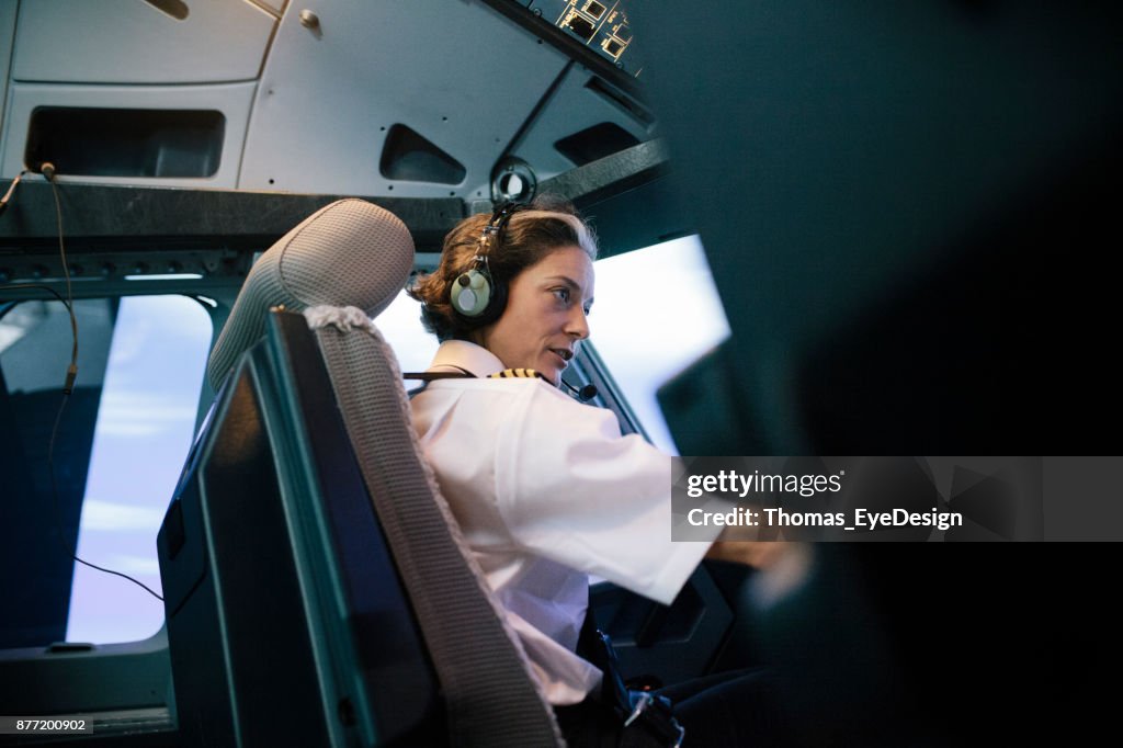 Flight Instructor Sitting In Simulator Cockpit Operating Aircraft