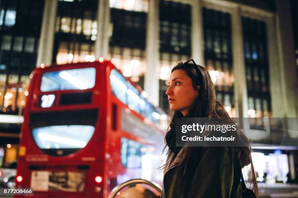 joven espera de transporte público en londres en la noche - clave baja fotografías e imágenes de stock