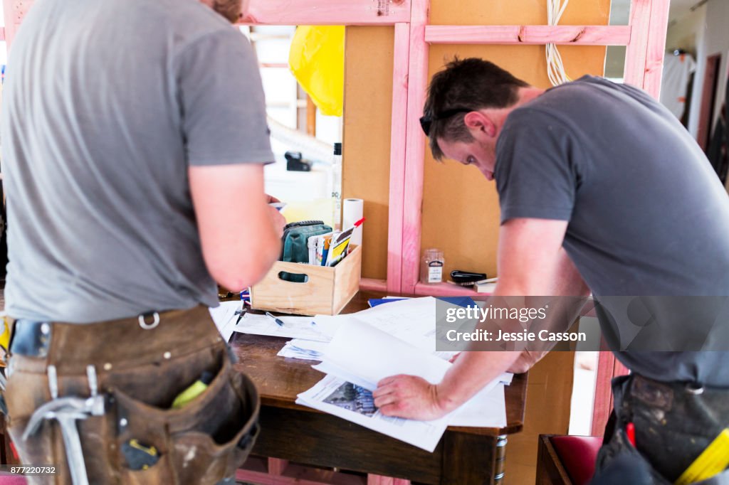 Two builders looks at building plans on construction site