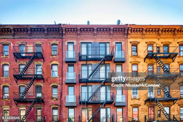 top stories of colorful williamsburg apartment buildings with steel fire escape stairways - condominio imagens e fotografias de stock