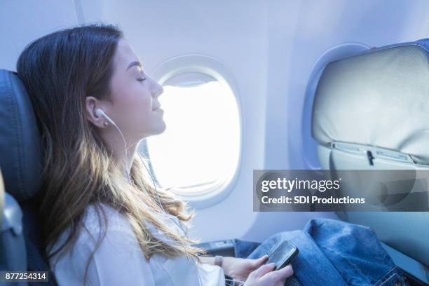 young woman rests with music during air travel - bending over backwards stock pictures, royalty-free photos & images