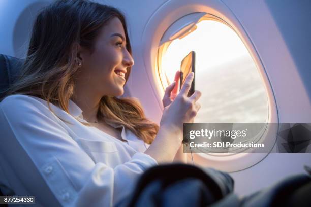 mooie jonge vrouw neemt sunset foto vanuit vliegtuig - raamplaats stockfoto's en -beelden