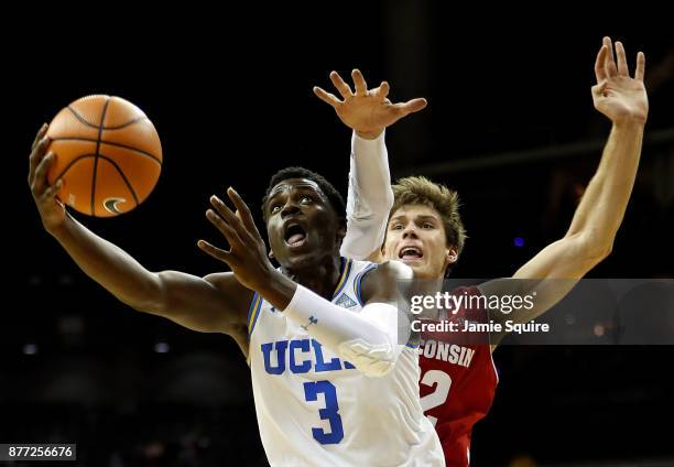 Aaron Holiday of the UCLA Bruins drives toward the basket as Ethan Happ of the Wisconsin Badgers defends during the National Collegiate Basketball...