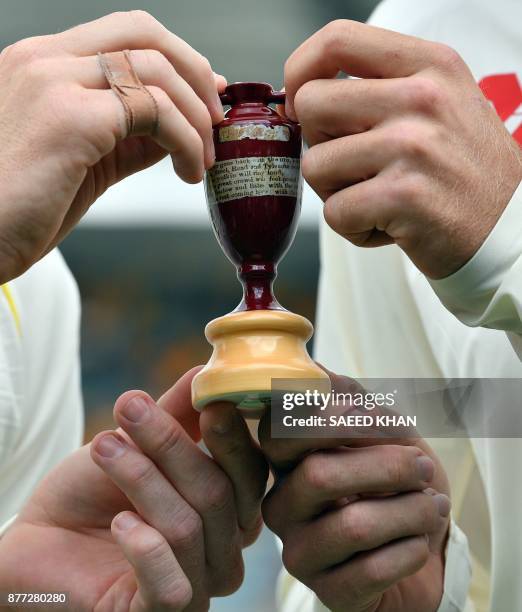 Australia's skipper Steve Smith and England captain Joe Root hold a replica Ashes Urn as they pose at a media opportunity in Brisbane on November 22...