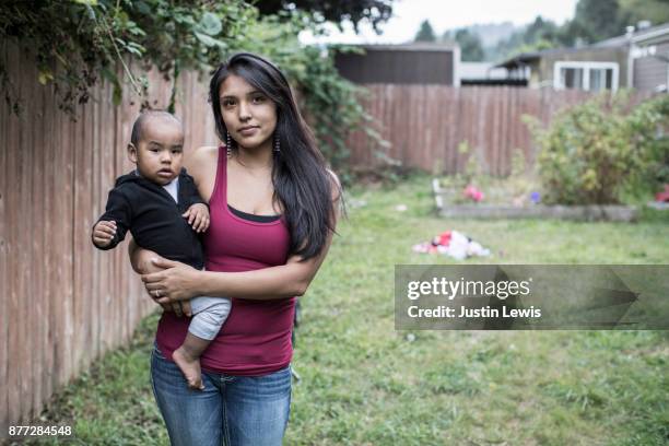 modern native american mom holds baby while standing in yard - indian family portrait stockfoto's en -beelden