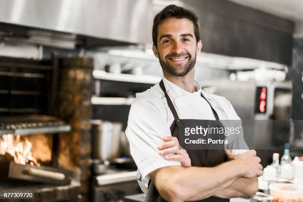 chef seguro de brazos de pie cruzan en cocina - cook fotografías e imágenes de stock