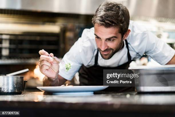 chef hombres guarnición de alimentos en cocina - cook fotografías e imágenes de stock