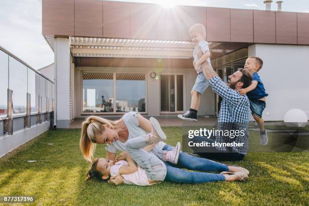 carefree family having fun while playing on a penthouse balcony. - penthouse girl stock pictures, royalty-free photos & images