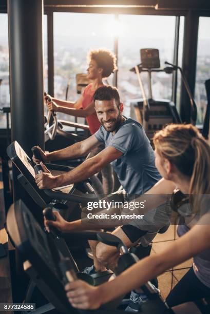 glücklich athleten während des trainings auf spinning bikes in einem fitnessstudio zu kommunizieren. - trainingsgerät stock-fotos und bilder