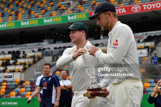 Australia's skipper Steve Smith and England captain Joe Root carry the Ashes trophy at a media opportunity in Brisbane on November 22 ahead of the...